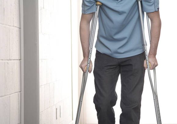 Young man using crutches in hospital.